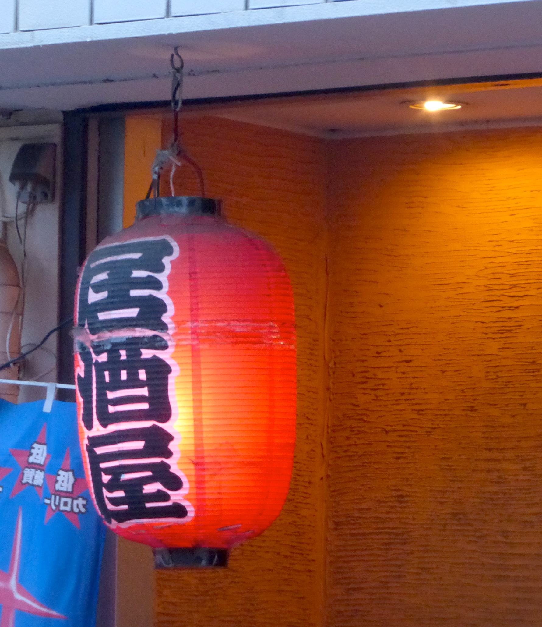 東京郊外の居酒屋、赤い提灯が灯る温かみのある外観