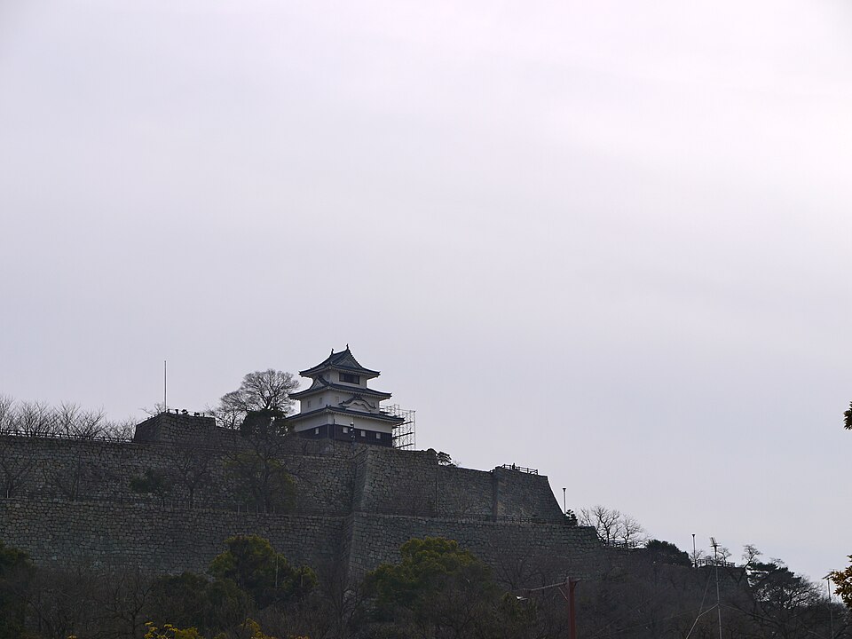 丸亀城への道、丸亀駅から城への徒歩ルートを示す街並みと城の石垣が見えるアングル